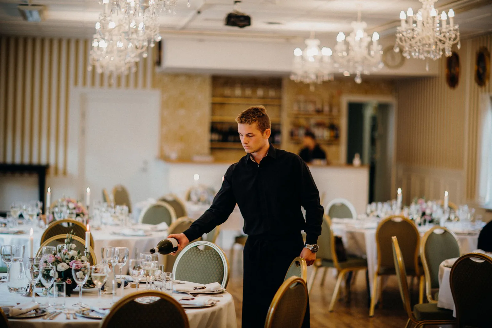 Elegant waiter pouring wine at catered event